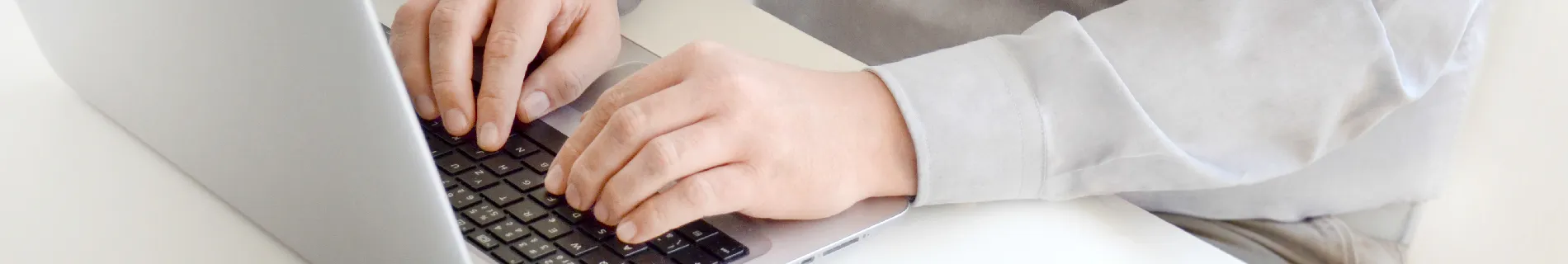 Ruce píšící na klávesnici notebooku